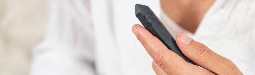 A person holds an Obsidian crystal point in their hand.