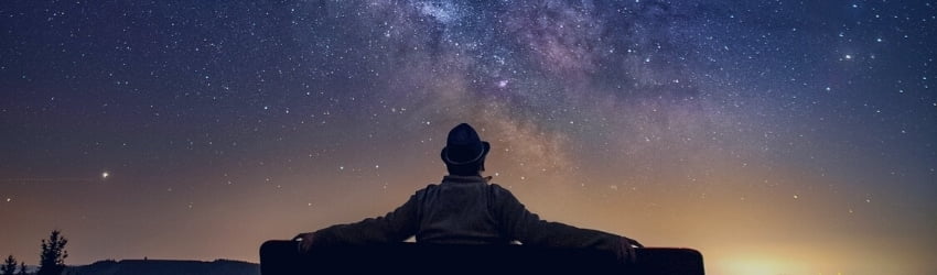 man sitting on a bench at night gazing at the stars