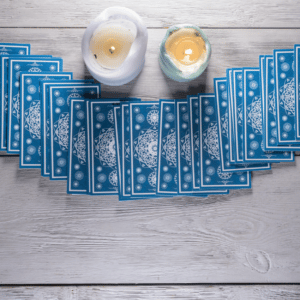 blue tarot cards spread out on a grey table with two candles