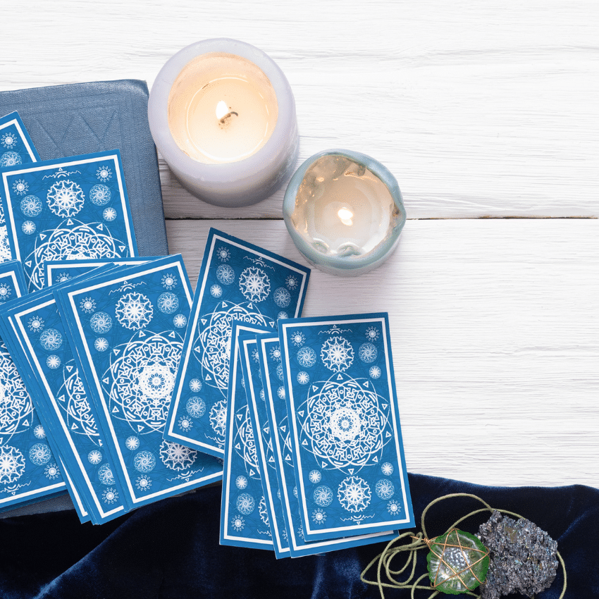 blue tarot cards spread on a white table with candles