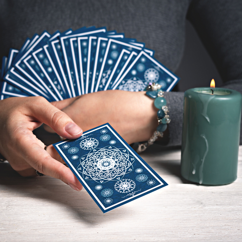 pair of hands holding a deck of blue tarot cards