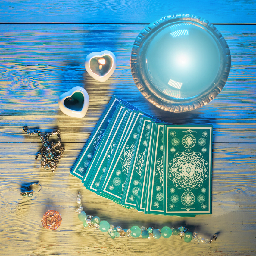 stack of blue tarot cards on a wooden table surronded by trinkets