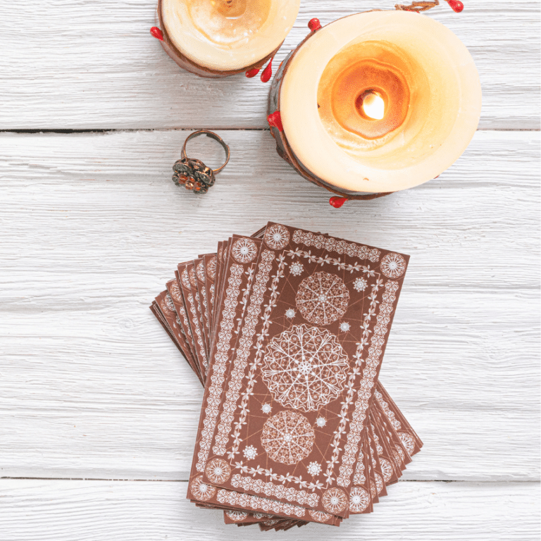 stack of brown tarot cards on a white table filled with candles