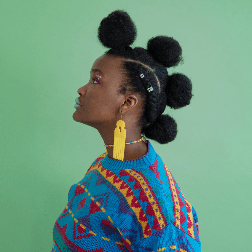 A black woman with a bright sweater stands with her side profile shown.