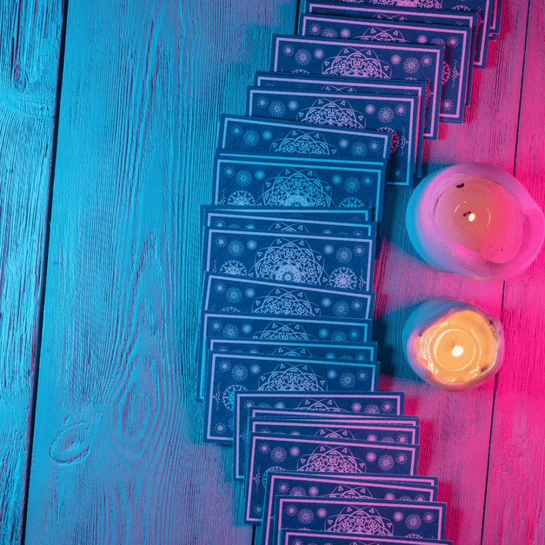 A line of Tarot cards face down next to 2 lit candles.