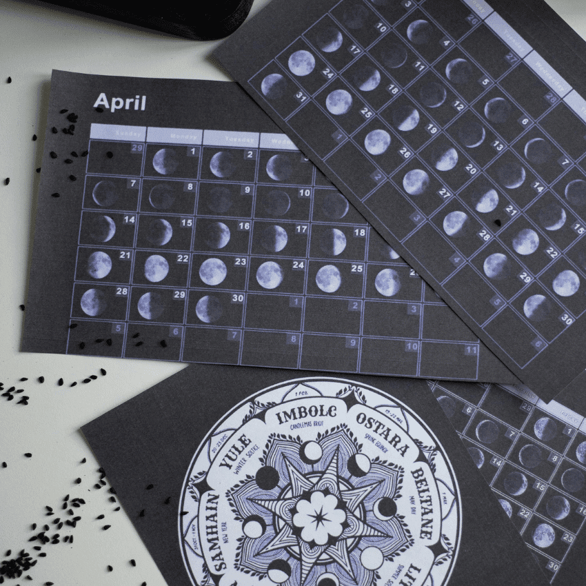 A lunar calendar featuring the month of April sits with some other papers on a table.