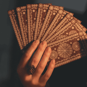 A hand holds a handful of brown Tarot cards, facing backwards.